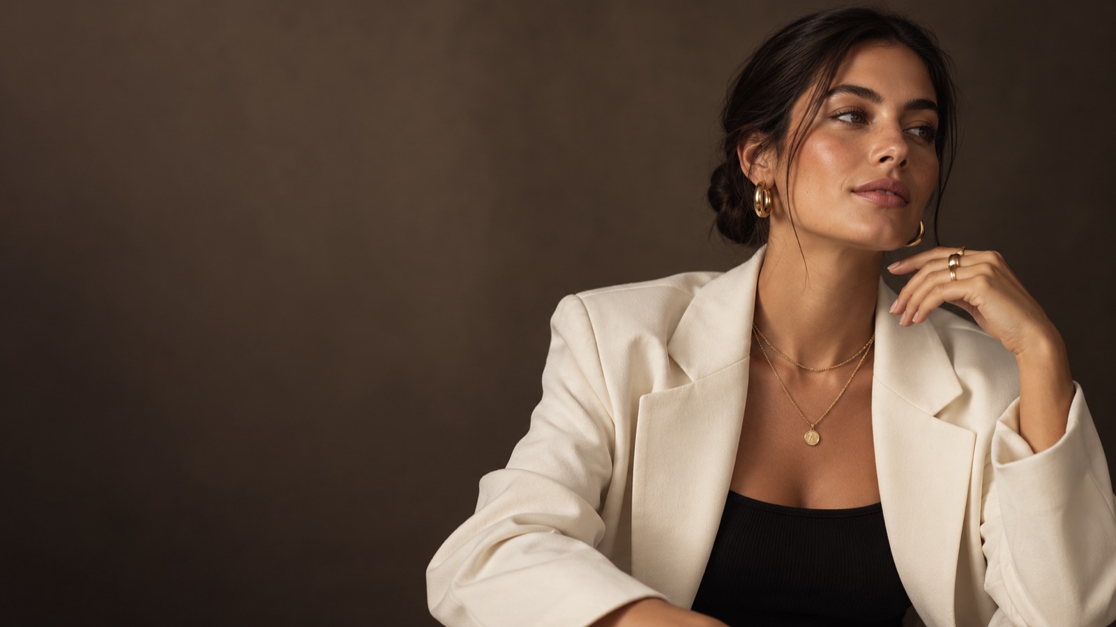 Woman wearing gold hoops, layered necklaces and rings